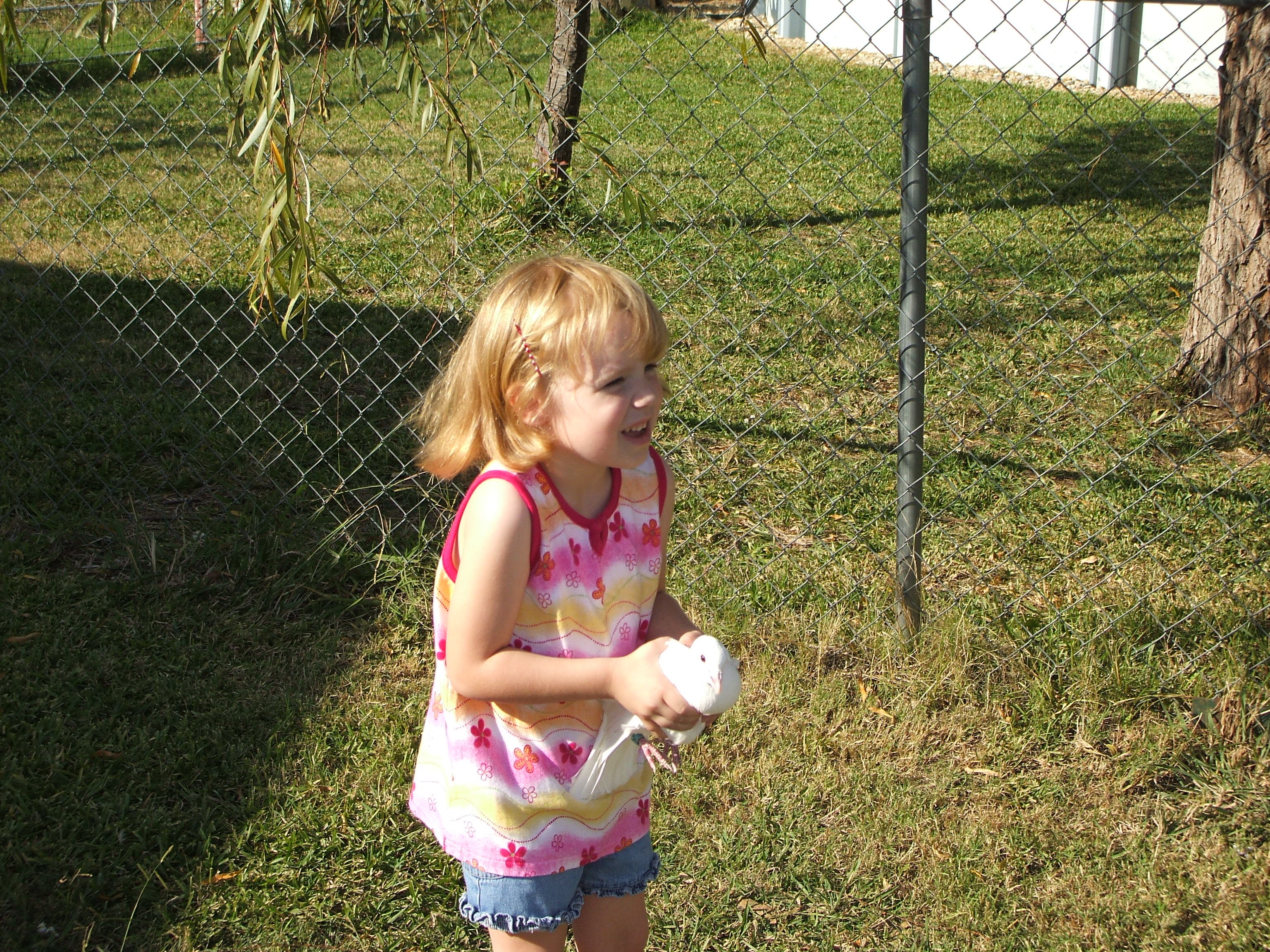 Child smiling while holding a white dove at a Doves 4 Yall special event